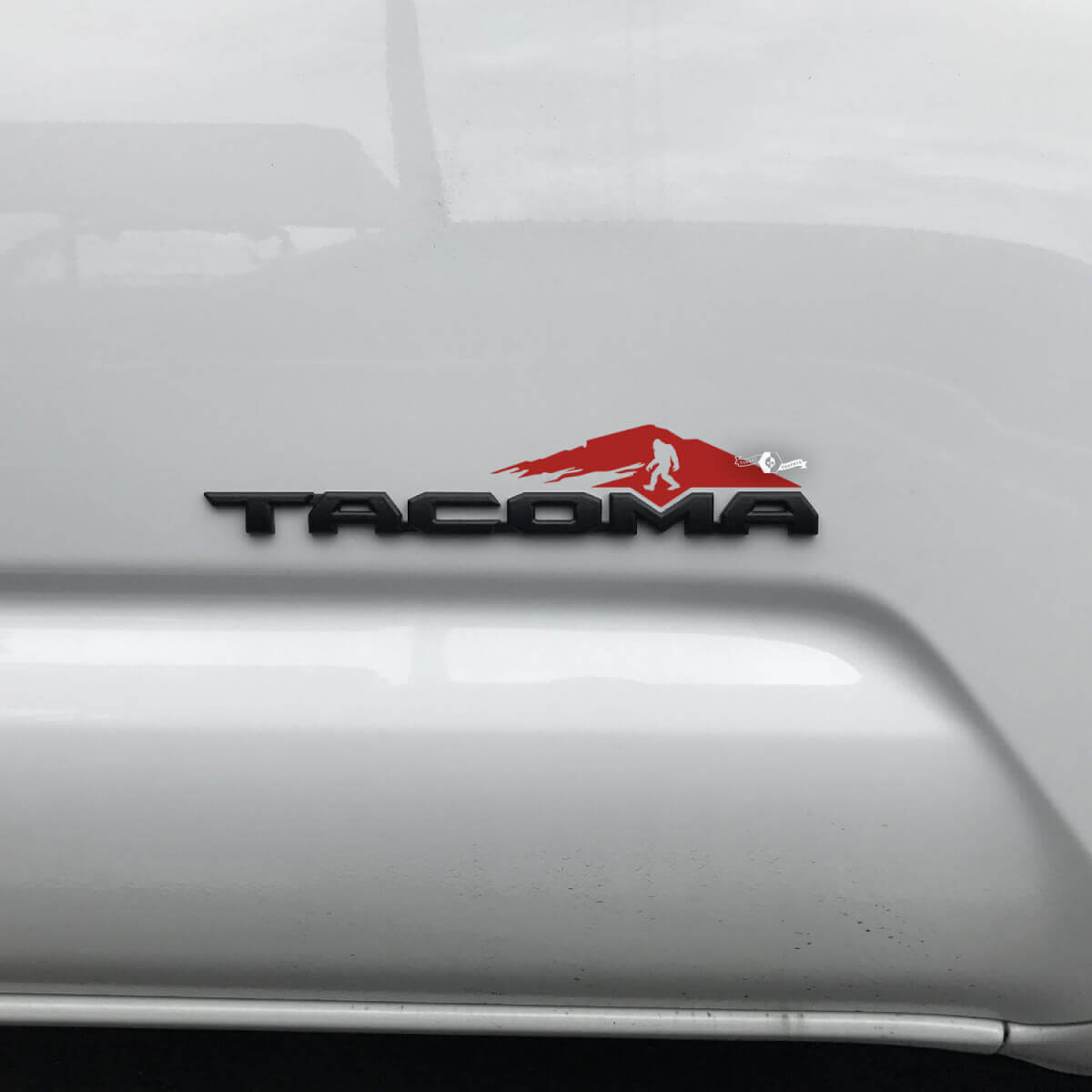 Etiqueta engomada de las montañas de Toyota Tacoma sobre la insignia Tacoma 2
